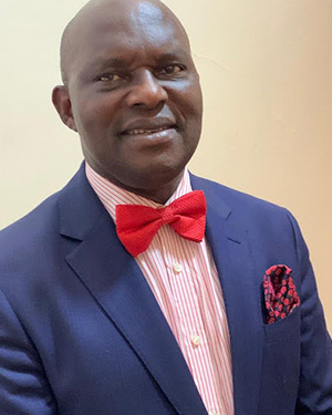 Smiling man in a blue suit with a red bowtie.